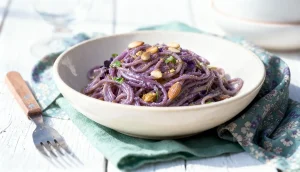 bord met paarse vijfgranen spaghetti met kool pesto en geroosterde broodkruimels, veganistisch Italiaans gerecht
