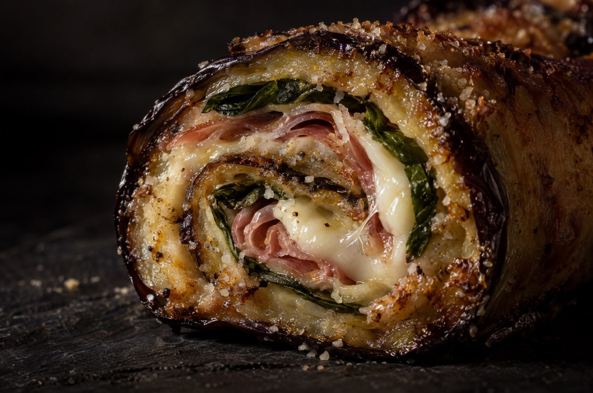 Doorsnede van auberginerol met een spiraal van aubergine, gesmolten provola en pancetta