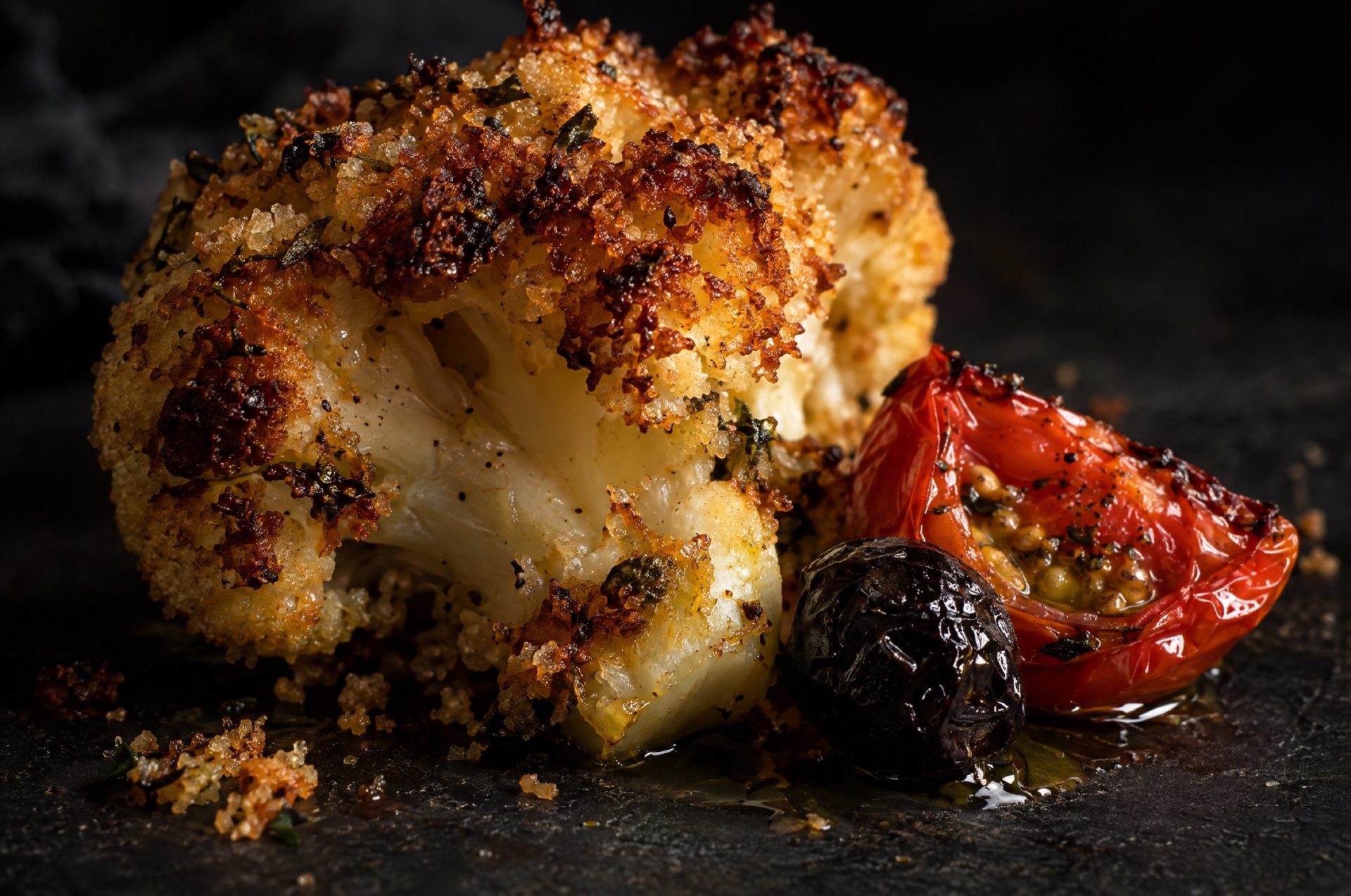 Closeup van bloemkool uit de oven alla marinara: goudbruine korst van broodkruim op een roosje met een glanzend tomaatje