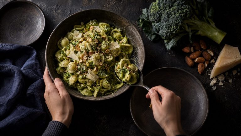 Orecchiette met broccolipesto op een leistenen tafel, met verse broccoli, amandelen en Parmigiano