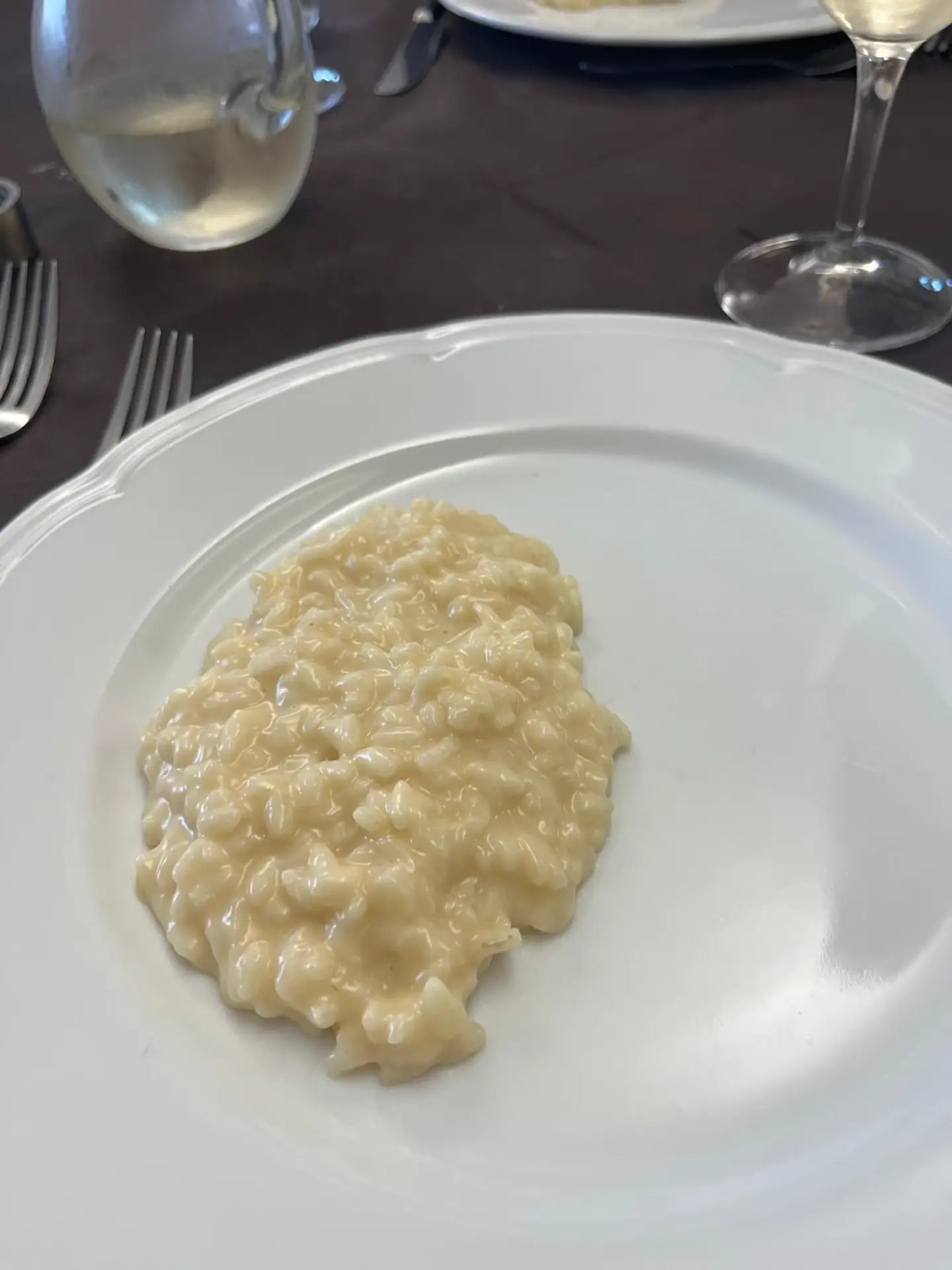 Romige risotto op wit bord met wijnglazen