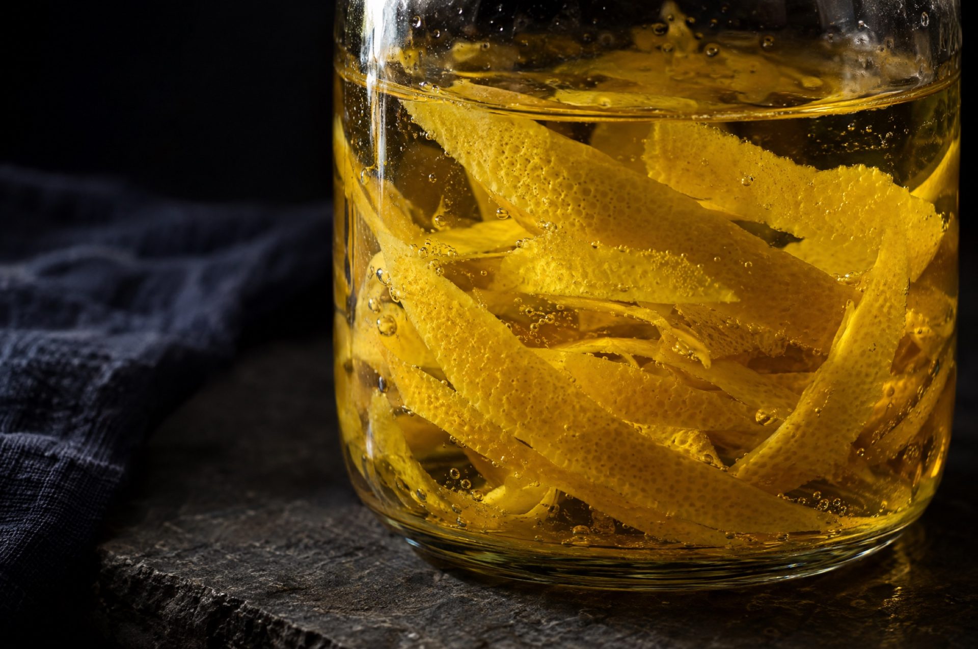 Close-up van limoncello: dunne gele citroenschillen zonder wit in heldere alcohol in een weckpot