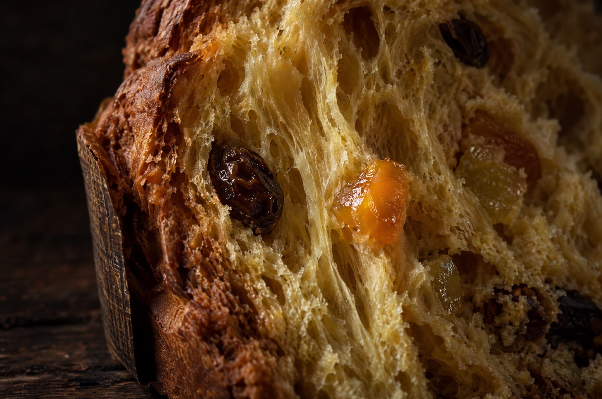 Doorsnede van panettone met lange gele luchtbellen in de kruim, rozijnen en blokjes gekonfijte sinaasappel