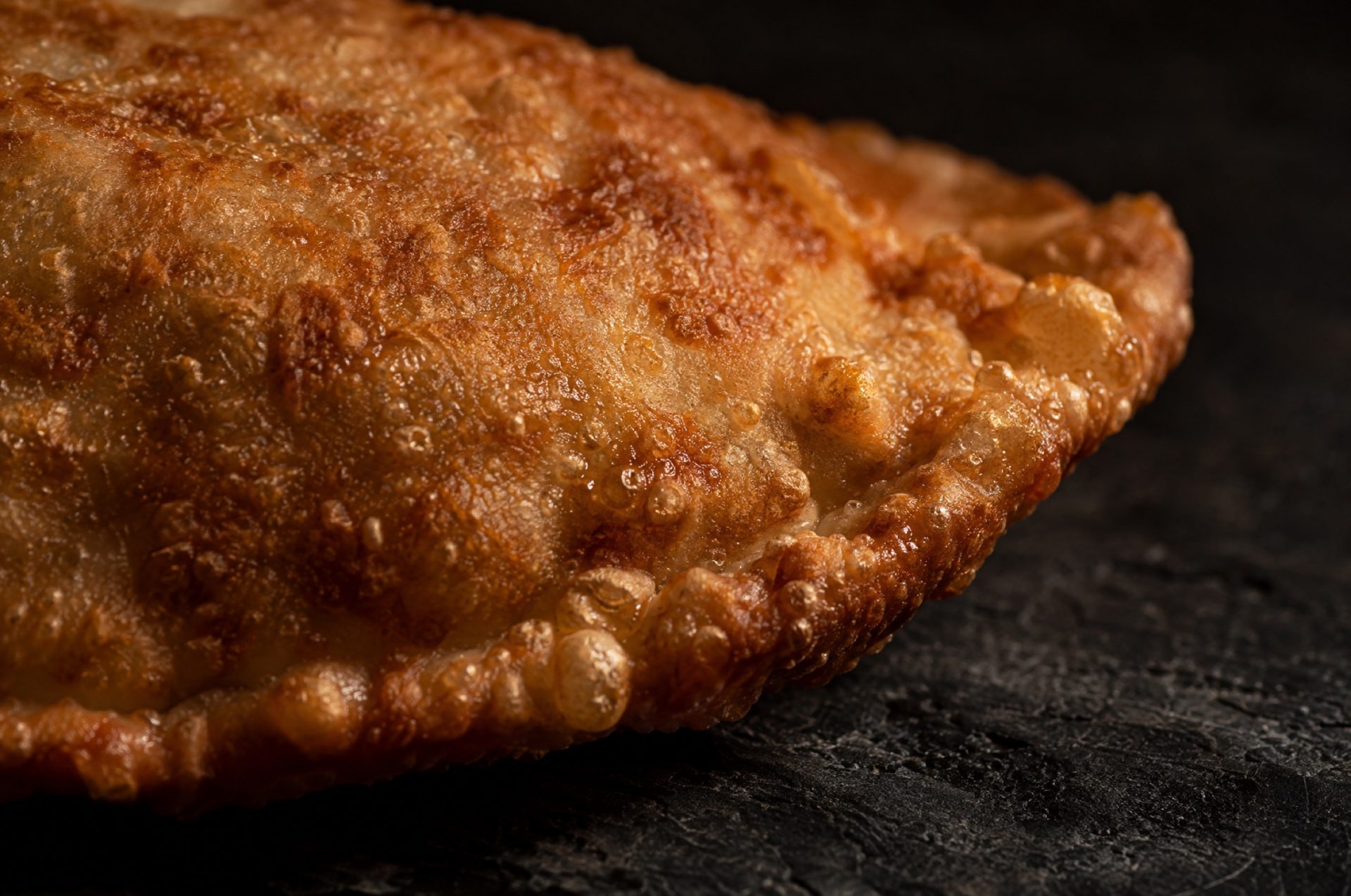 Macro van de goudbruine korst van een pizza fritta, met kleine luchtbellen in het gefrituurde deeg