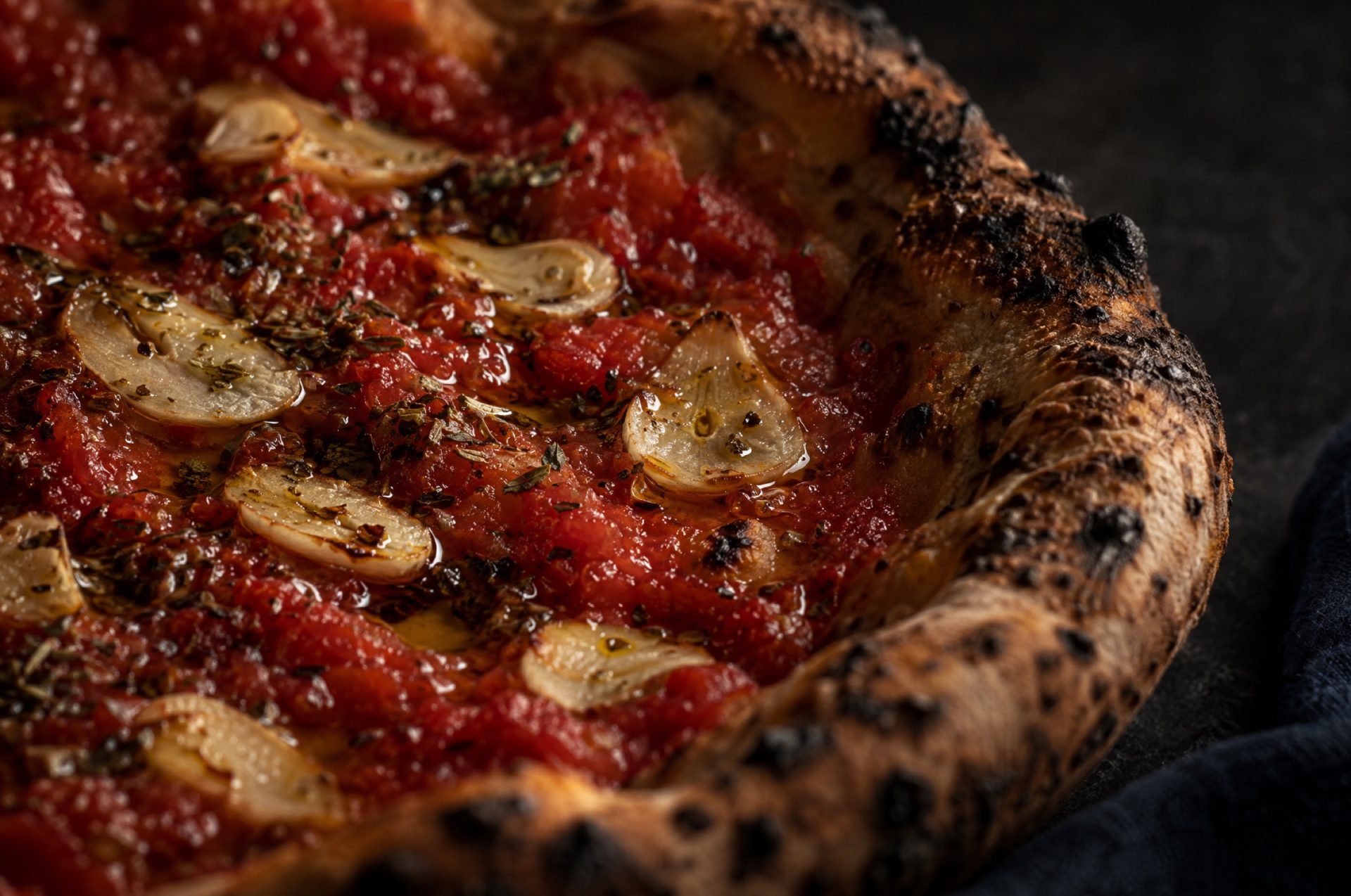 Close-up van een pizza marinara met dunne plakjes knoflook in de rode tomaat en olijfolie die glanst