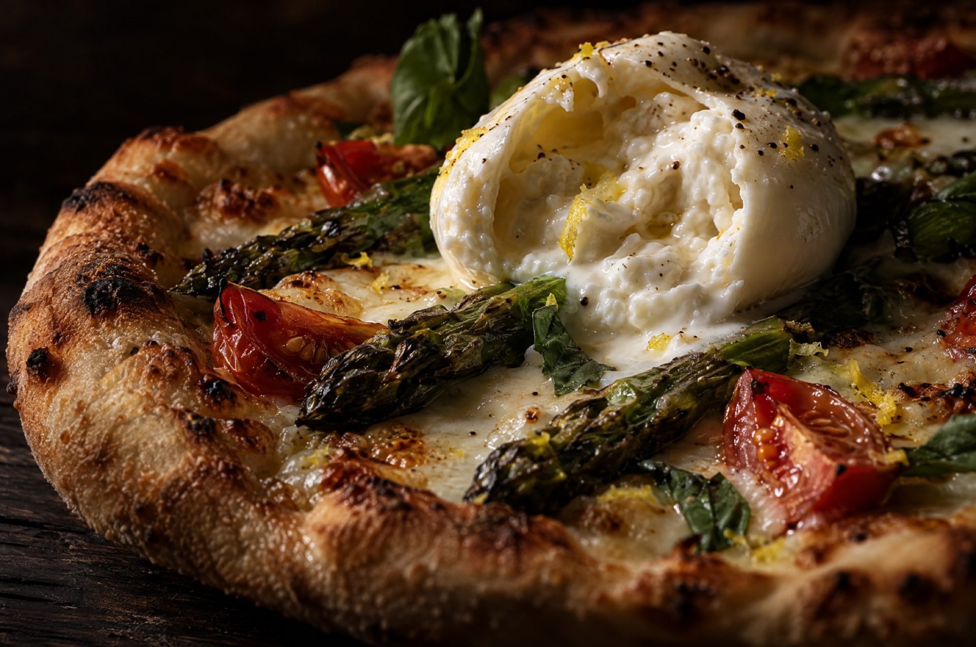 Close-up van pizza met asperges, met geroosterde aspergepunten, gesmolten mozzarella en een opengesneden burrata