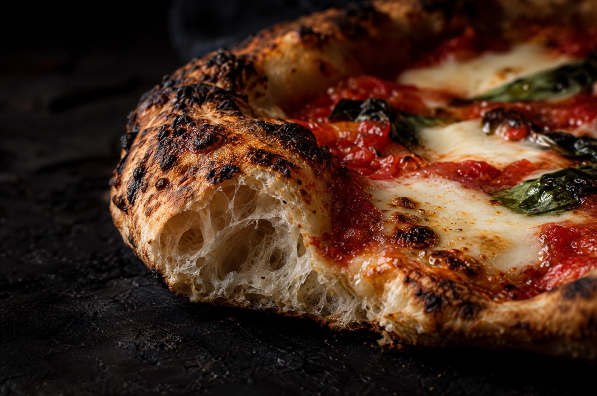 Close-up van de gevlekte rand van pizza op de bbq, met luchtbellen in de korst en gesmolten fior di latte