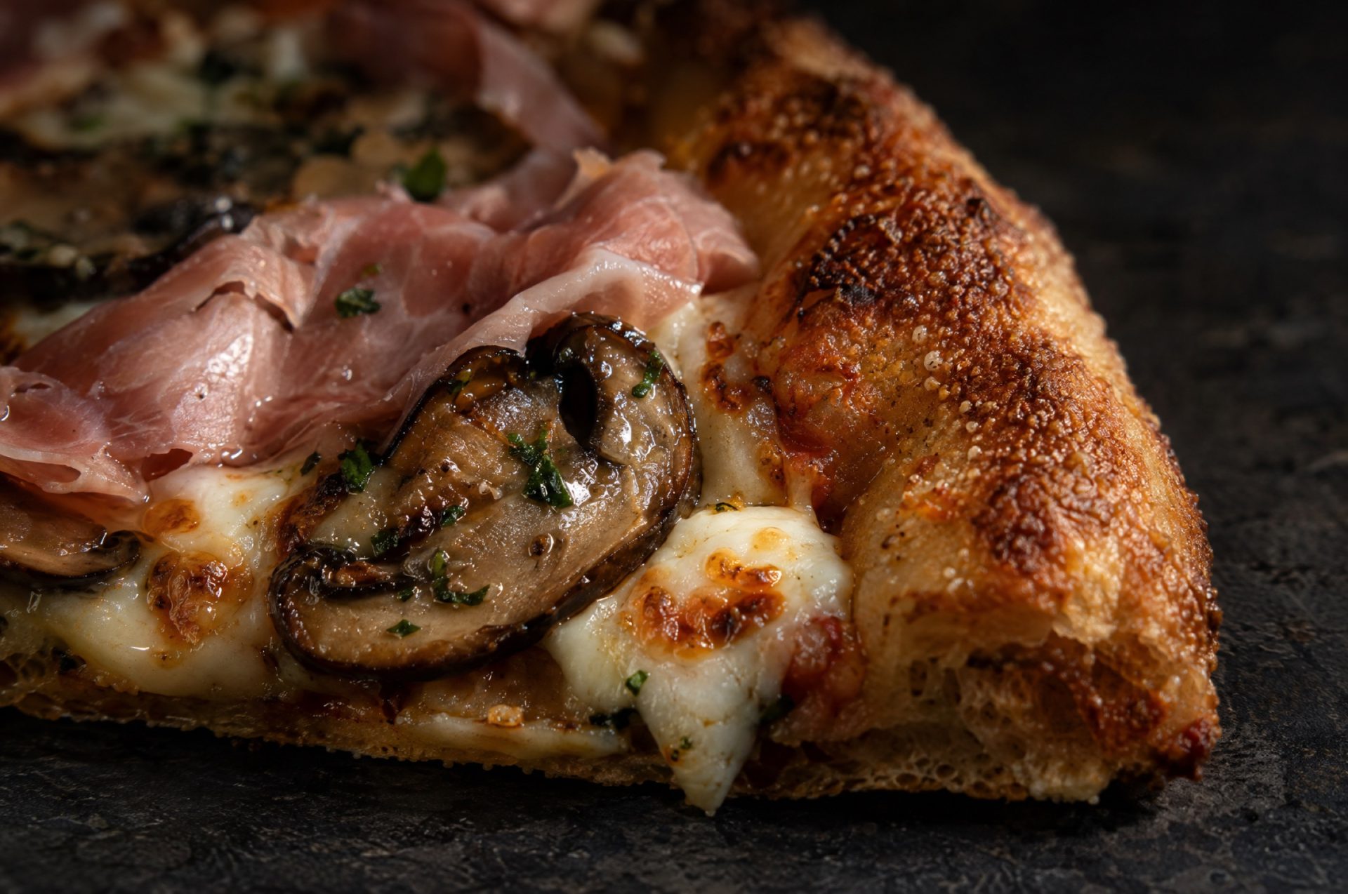 Close-up van pizza prosciutto e funghi: gesmolten mozzarella, gebakken champignons en de bruine, krokante rand