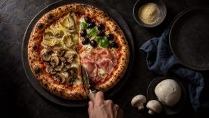 Pizza quattro stagioni van bovenaf met vier kwarten: artisjok, olijven met basilicum, champignons en prosciutto cotto